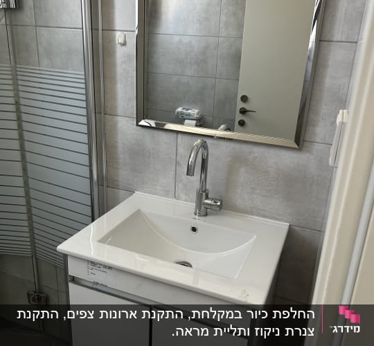 כיור אמבטיה עם מראה וברז בחדר רחצה